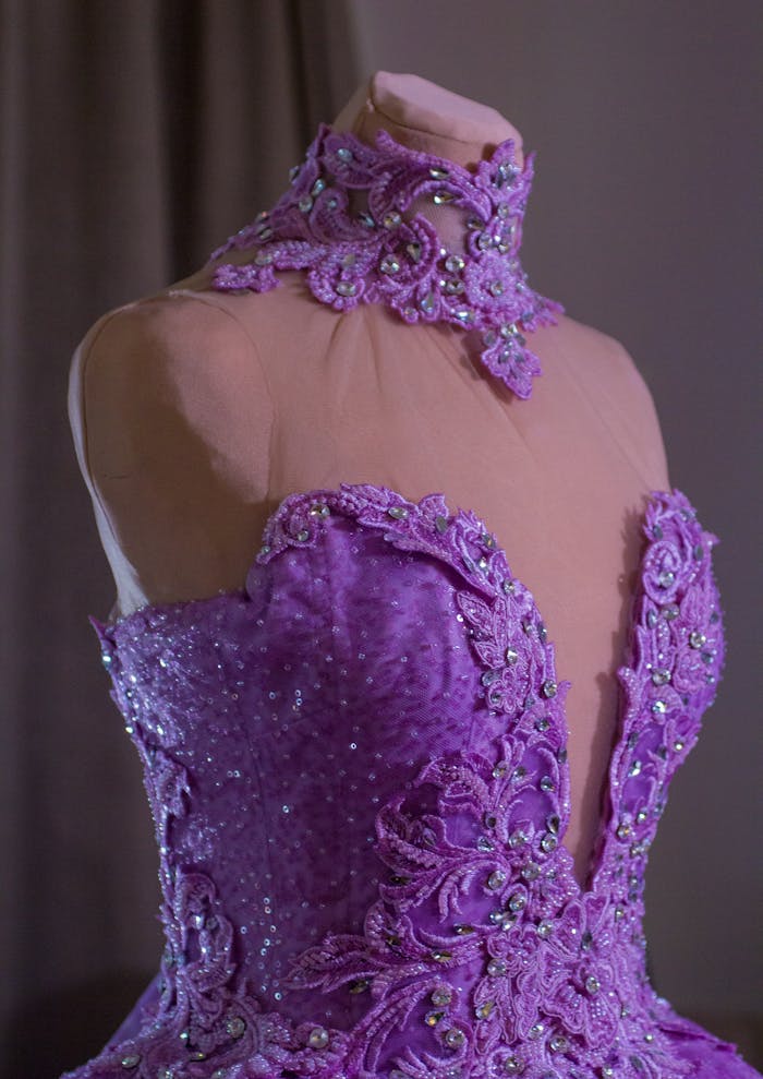 Close-up of an elegant purple bridal gown on mannequin with intricate lace details.