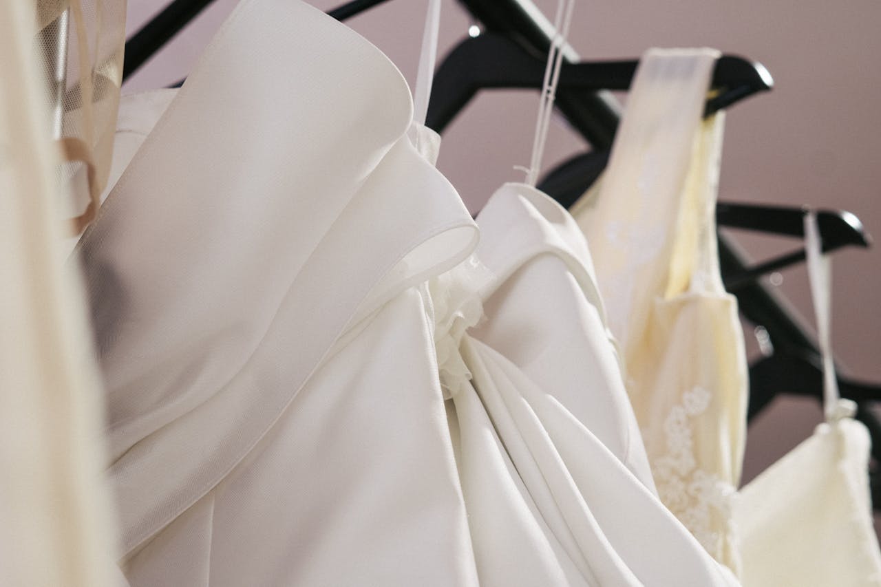 Close-up of elegant wedding gowns hanging in a bridal shop, showcasing intricate details and fabric.